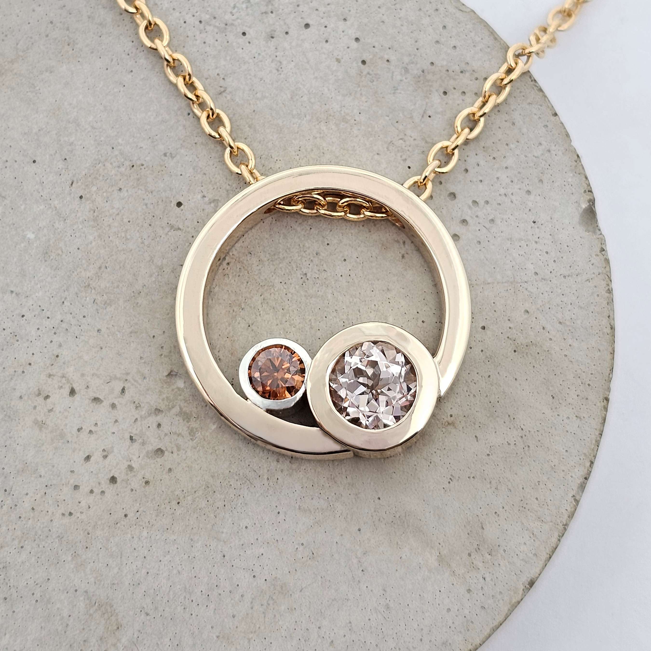 Yellow gold pendant with circular design, featuring a blush morganite and a rich chocolate diamond bezel-set side by side.