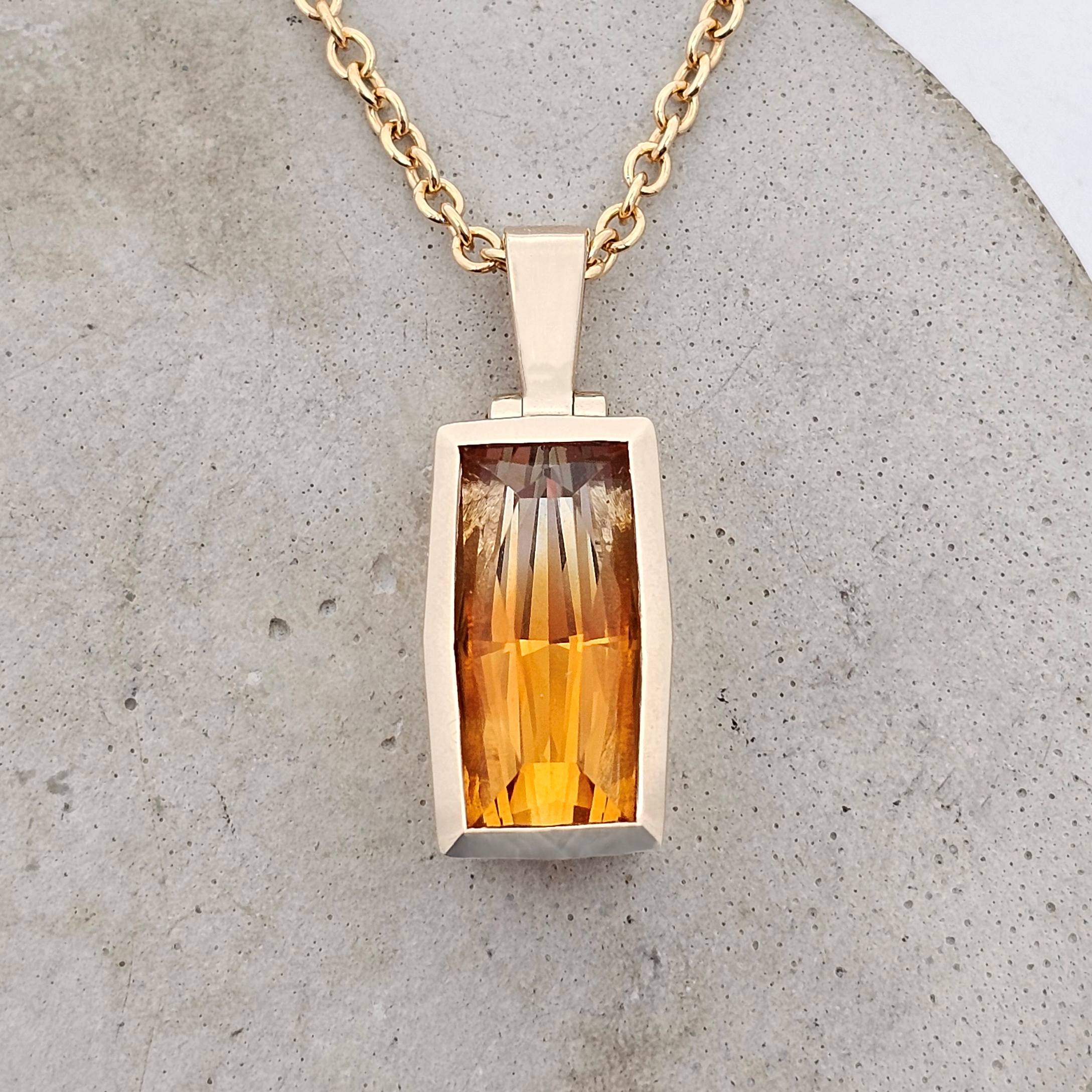 Bi-colour citrine pendant featuring a rectangular faceted gemstone with golden to amber tones, set in a bold structured gold setting.