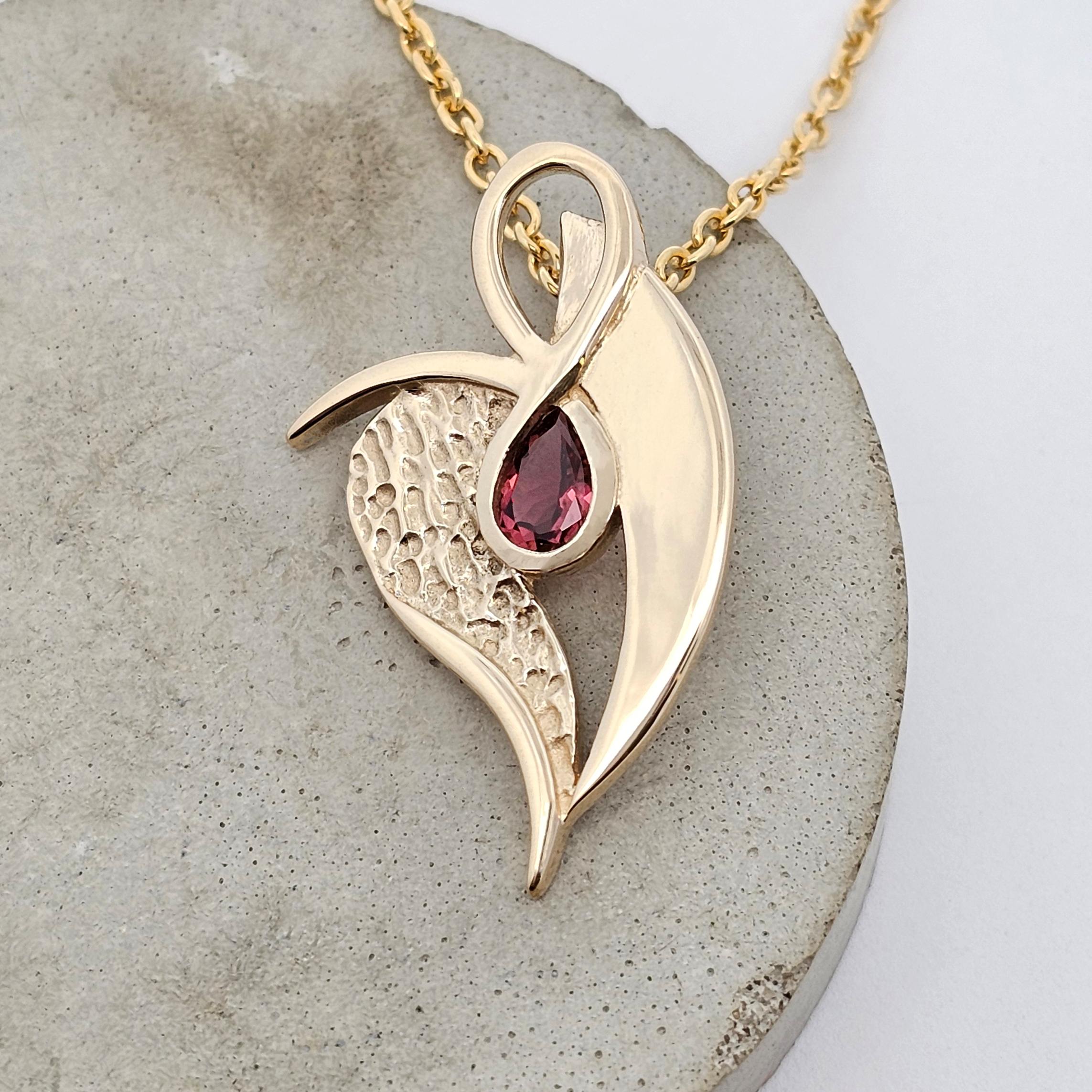 Sculptural yellow gold pendant featuring a pear-shaped pink tourmaline and contrasting polished and hammered textures.