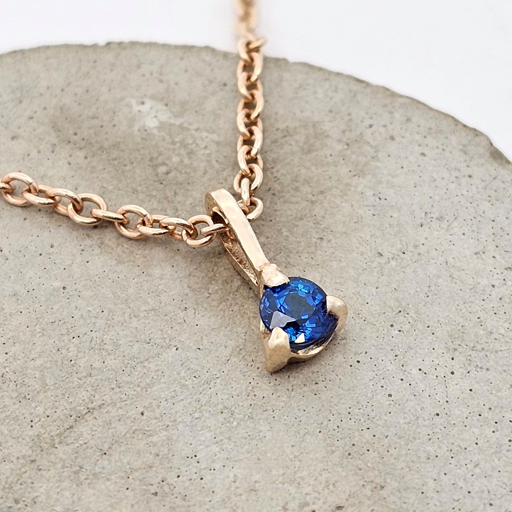 9ct yellow gold pendant featuring a natural round blue sapphire in a classic three-claw setting.