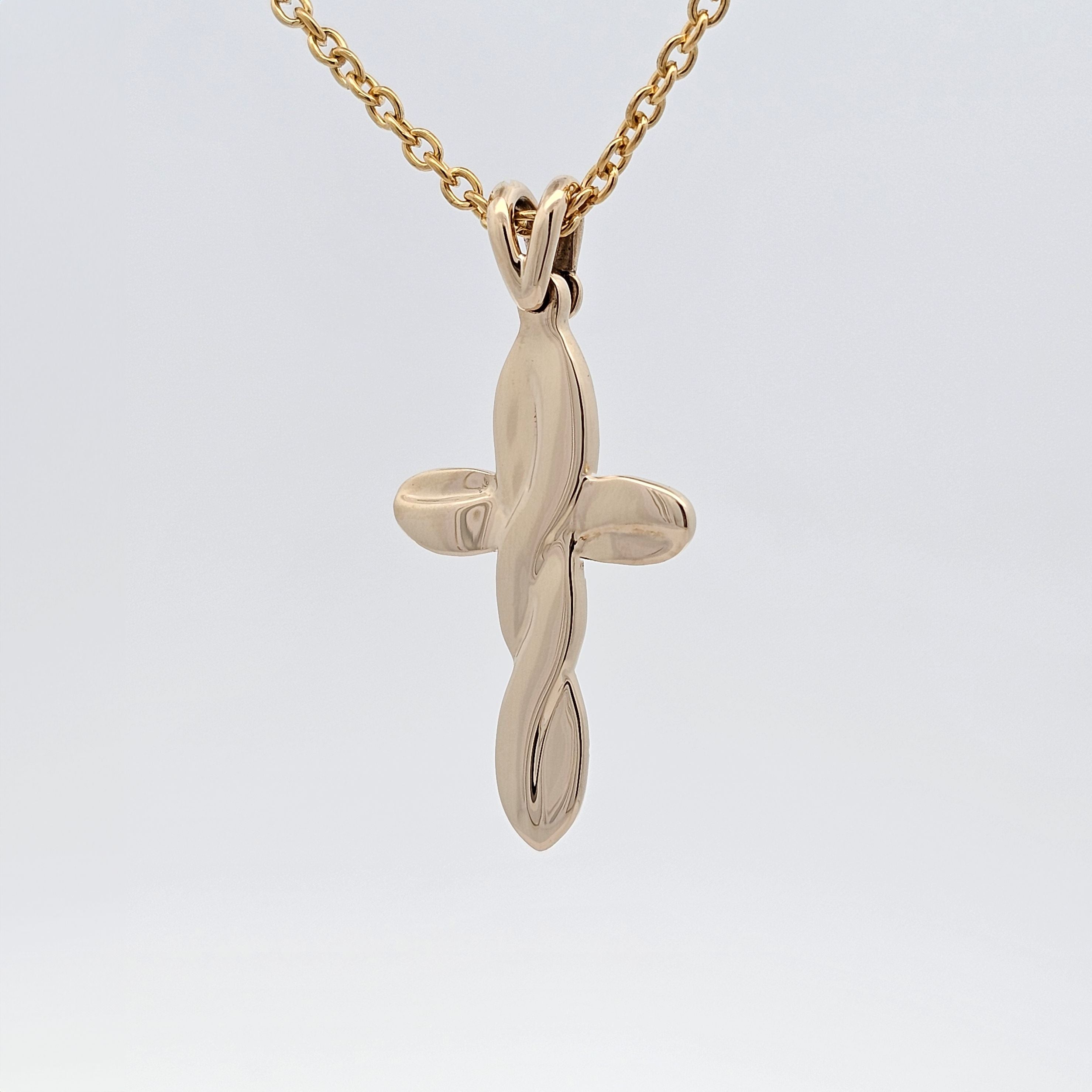 Yellow gold cross pendant with flowing sculptural design, modern twist on a timeless symbol.