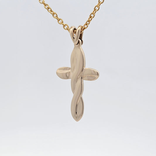 Yellow gold cross pendant with flowing sculptural design, modern twist on a timeless symbol.
