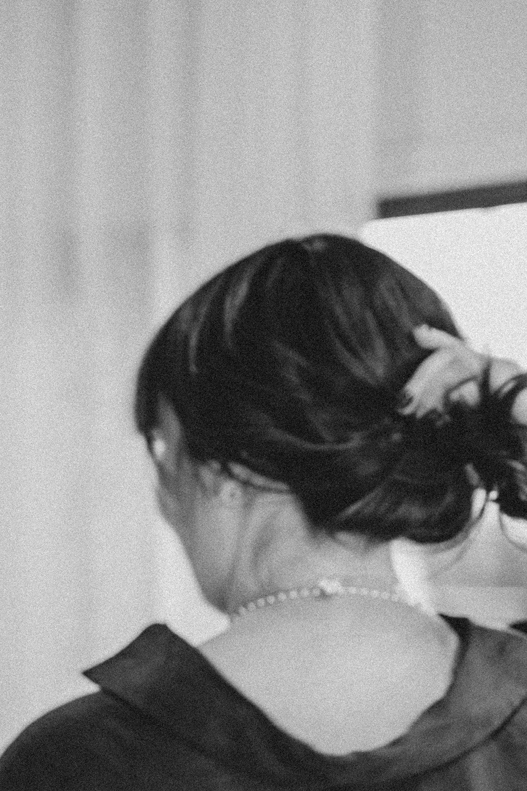 Person adjusting their hair in a black and white photo